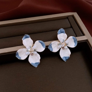 Close-up of flower earrings with blue enamel drip oil finish and crystal center