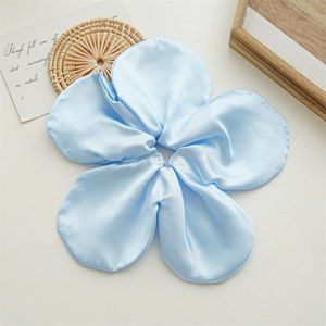 Detail of light blue satin flower scrunchie on a white table with natural decor
