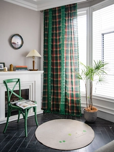 Detail of red and green plaid curtain with green lace trim and decorative tassels