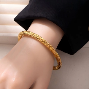 Macro detail of 18K gold plated twisted rope cuff bracelet with textured metal finish