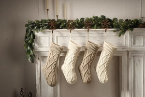 Detailed texture of ivory and oatmeal knit Christmas stockings hanging on a white fireplace