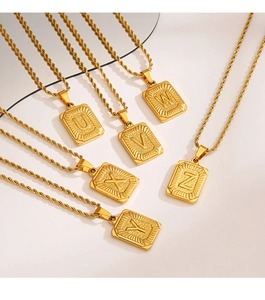 Vue détaillée de pendentifs carrés dorés avec lettres U à Z sur chaînes torsadées