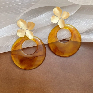 Detail view of flower resin drop earrings with golden metal petals and amber hoop charms