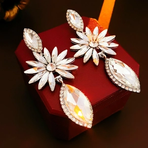 Détail des boucles d'oreilles en cristal avec motif floral argenté sur boîte rouge