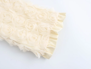 Detail of delicate 3D rose appliques and mesh fabric on cream cardigan sleeve