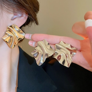 Close-up of gold irregular wrinkled metal earrings showing reflective texture and design