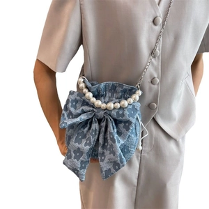 Blue floral shoulder bag with large pearl handle and metal chain strap on model