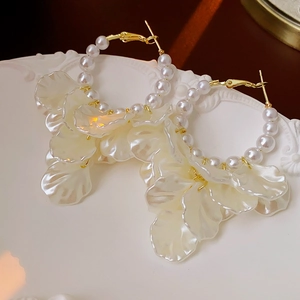 Détail de boucles d'oreilles vintage en perles avec pétales de nacre sur assiette blanche