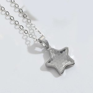 Macro shot of a silver star-shaped pendant necklace with glittery texture on white background