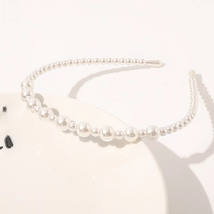 Detail showing elegant white pearls in alternating sizes on a slim metal headband frame