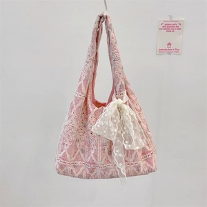 Detail of pink canvas bag featuring delicate lace embroidery and a white ribbon bow