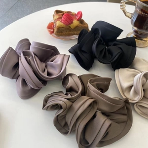 Close-up of four oversized pleated hair scrunchies in purple, black, coffee, and beige colors