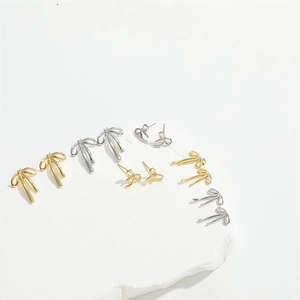 Fashionable gold and silver bow earrings with crystals on white stone pedestal