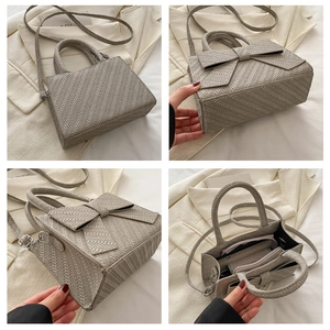 Detail view of woven textured handbag featuring a large bow and internal compartments