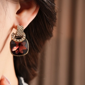 Close-up of vintage gold C-shape earrings featuring red square crystals and rhinestones