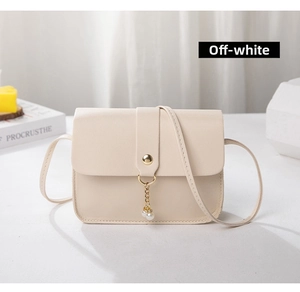 Detailed view of the off-white crossbody bag featuring a pearl charm and golden clasp closure