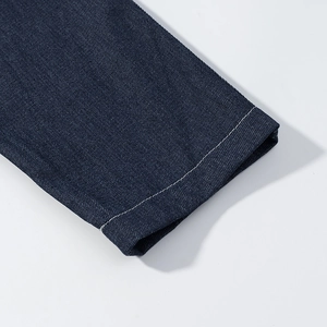 Detailed macro view of dark blue denim cuff with white double stitching and texture