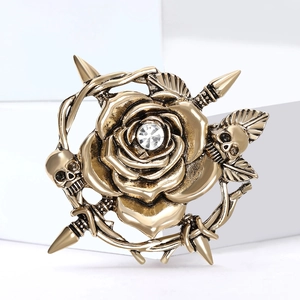 Vintage gold skull and rose brooch featuring clear crystal accents and sharp vine details