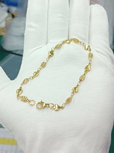 Detail of gold heart and hollow oval link chain with lobster clasp on a gloved hand