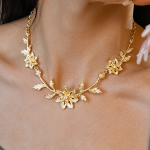 Detail of golden floral statement necklace with leaf accents on woman's neckline
