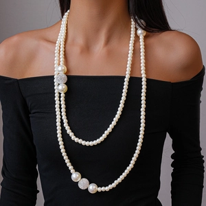 Detail of layered pearl necklace with shimmering rhinestone studded spheres on black dress
