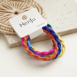 Close-up of candy-colored braided elastic hair ties in a multi-color set on straw mat