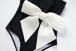 Detailed view of a white bow knot decoration on a black contrast one-piece swimsuit