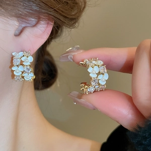 Elegant gold flower stud earrings with pearls and zircons shown on a model