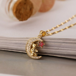 Gold moon bear pendant necklace with white zircon and red star on open book page