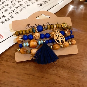 Detail of bohemian layered sandalwood bracelets with blue silk tassel and tree of life charm