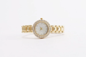 Nahaufnahme einer Damen-Quarzuhr in Gold mit einer Lünette und Zifferblatt mit Kristallen