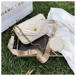 Detail of white quilted crossbody bag with gold chain and round pouch on grass