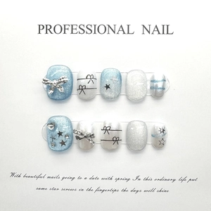 Détail de faux ongles faits main bleu et blanc pailleté avec nœuds 3D argentés