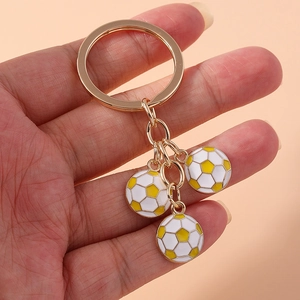 Close-up of golden keychain featuring three white and yellow soccer ball pendants