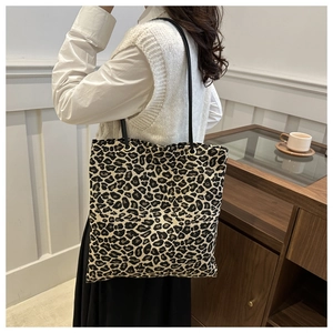 Detailed close-up of a leopard print tote bag with a slim black shoulder strap on a model