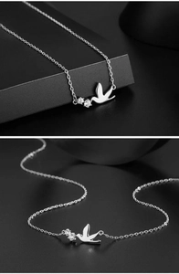 Macro shot of silver swallow bird pendant necklace with clear zircon stones on black background