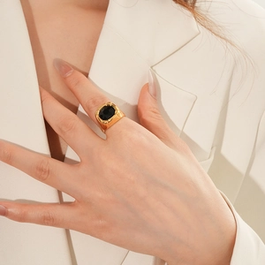 Dettaglio anello vintage dorato con gemma ovale nera indossato sul dito indice