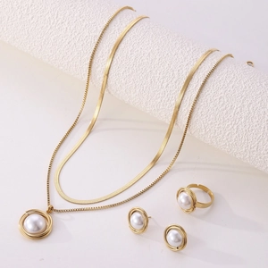 Close-up of golden mesh necklace, pearl earrings and ring set on minimalist white surface