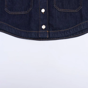 Détails de denim bleu foncé avec des coutures orange et un bouton métallique argenté brillant