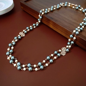 Close-up of double-layered pearl necklace with blue pearls and gold floral accents