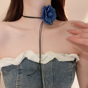 Close-up of a blue denim flower choker necklace with black ribbons on a model neck