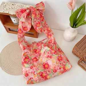 Detailed macro view of floral tote bag featuring a large bow and drawstring closure