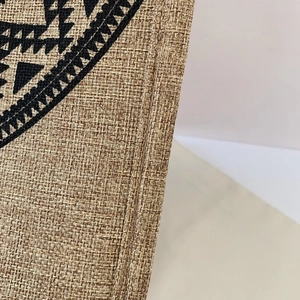 Macro shot of ethnic linen bag texture with reinforced stitching and black geometric patterns