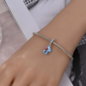 Detail of silver snake chain bracelet featuring blue enamel mixer charm with blue zircons