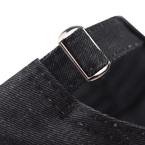 Detail of black cotton baseball cap showing adjustable strap with silver metal buckle