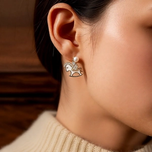 Gros plan d'une boucle d'oreille cheval à bascule plaquée or 14k avec perle et zircon
