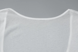 Dettaglio della trama in maglia bianca a coste e scollatura di un abito estivo sottile