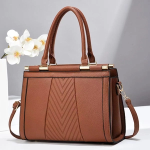Détail du sac marron en cuir grainé avec gaufrage en V et ferrures dorées élégantes