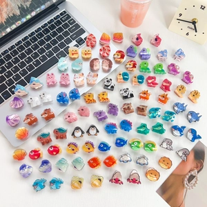 Mini acrylic animal hair clips set featuring cute panda and dinosaur shapes on a white desk