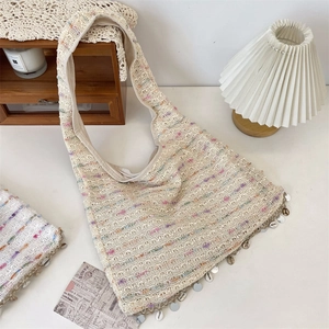 Detail of beige crochet tote bag with colorful stripes and dangling seashell charms